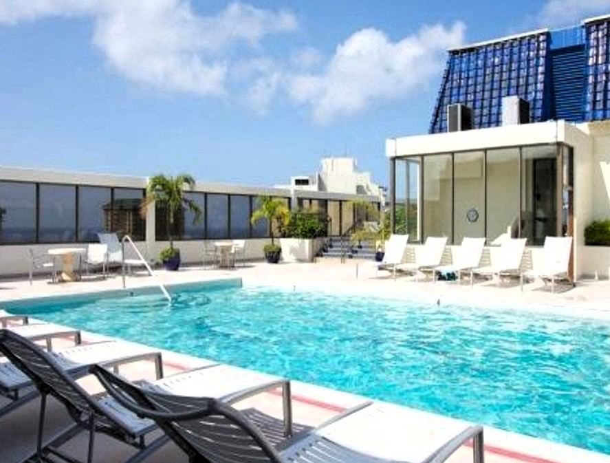 A pool with chairs around it and a building in the background.